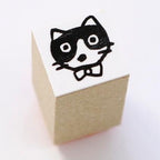 Wooden cube stamp featuring chibi cat with glasses and bowtie by Yumi Kitagishi