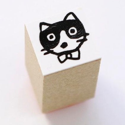 Wooden cube stamp featuring chibi cat with glasses and bowtie by Yumi Kitagishi