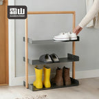 Lifestyle shot of three-tier shoe rack holding sneakers, slippers, and boots in an entryway with light wood frame