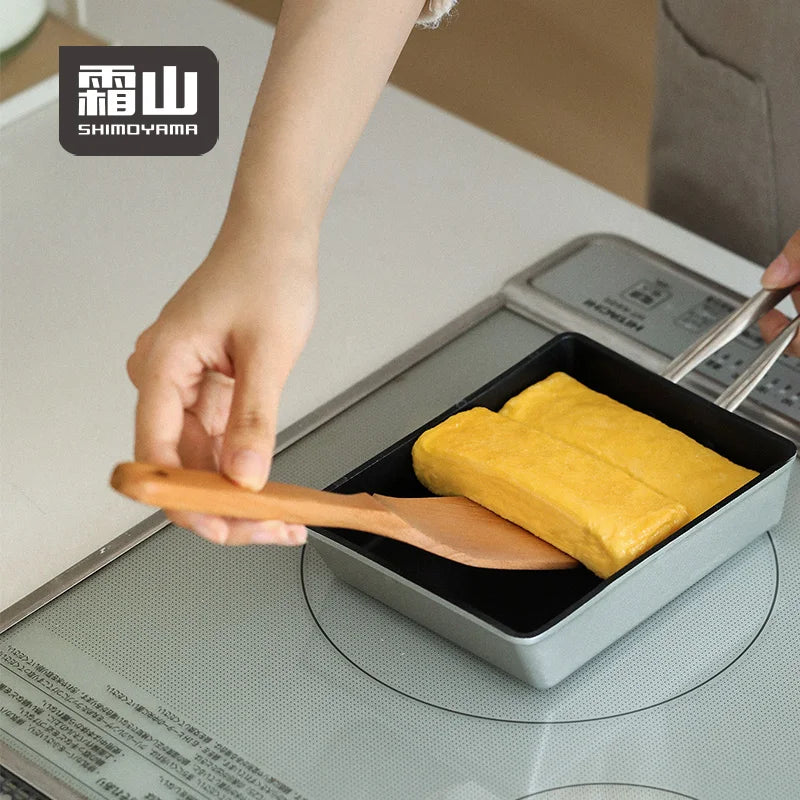 Lifting rolled omelet with square beech spatula from rectangular pan