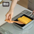 Lifting rolled omelet with square beech spatula from rectangular pan