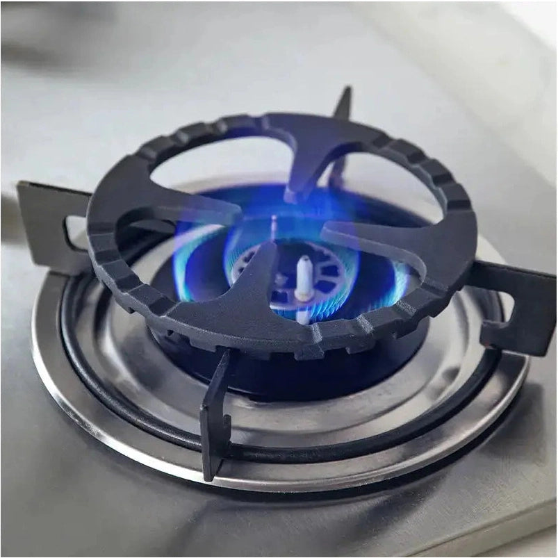 Black cast iron trivet stabilizing small pot on gas stove burner
