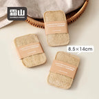 Three packaged loofah dish wipes next to linen cloth and wicker basket