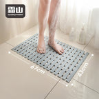 Bare feet on grey non-slip bath mat under running water, showing 67x43cm size