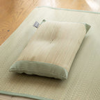 Olive green cotton trimmed rush straw pillow resting on matching mat