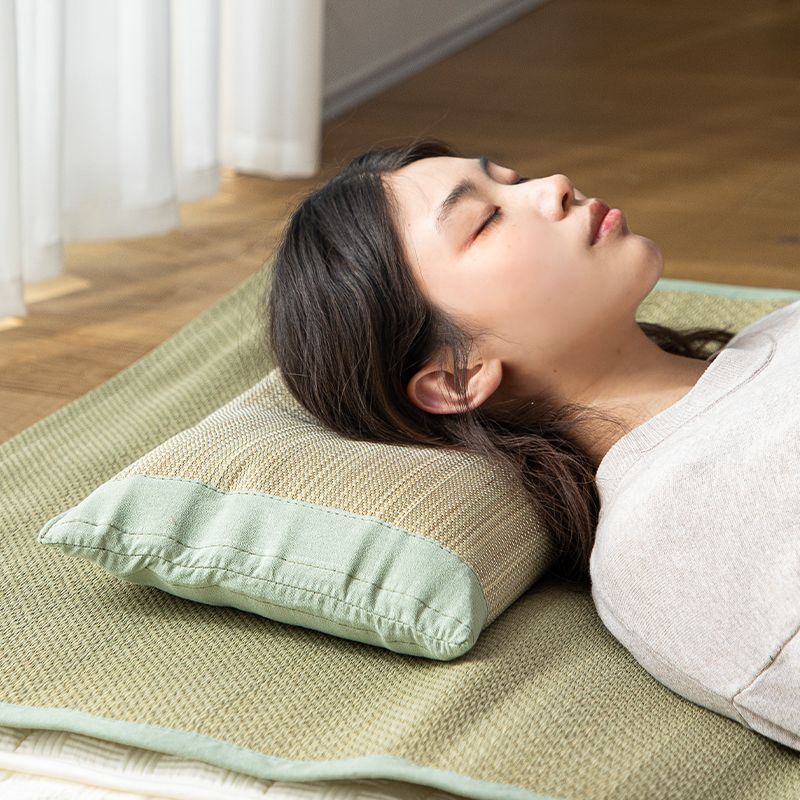 Person sleeping on side using beige rush straw pillow with green cotton borders