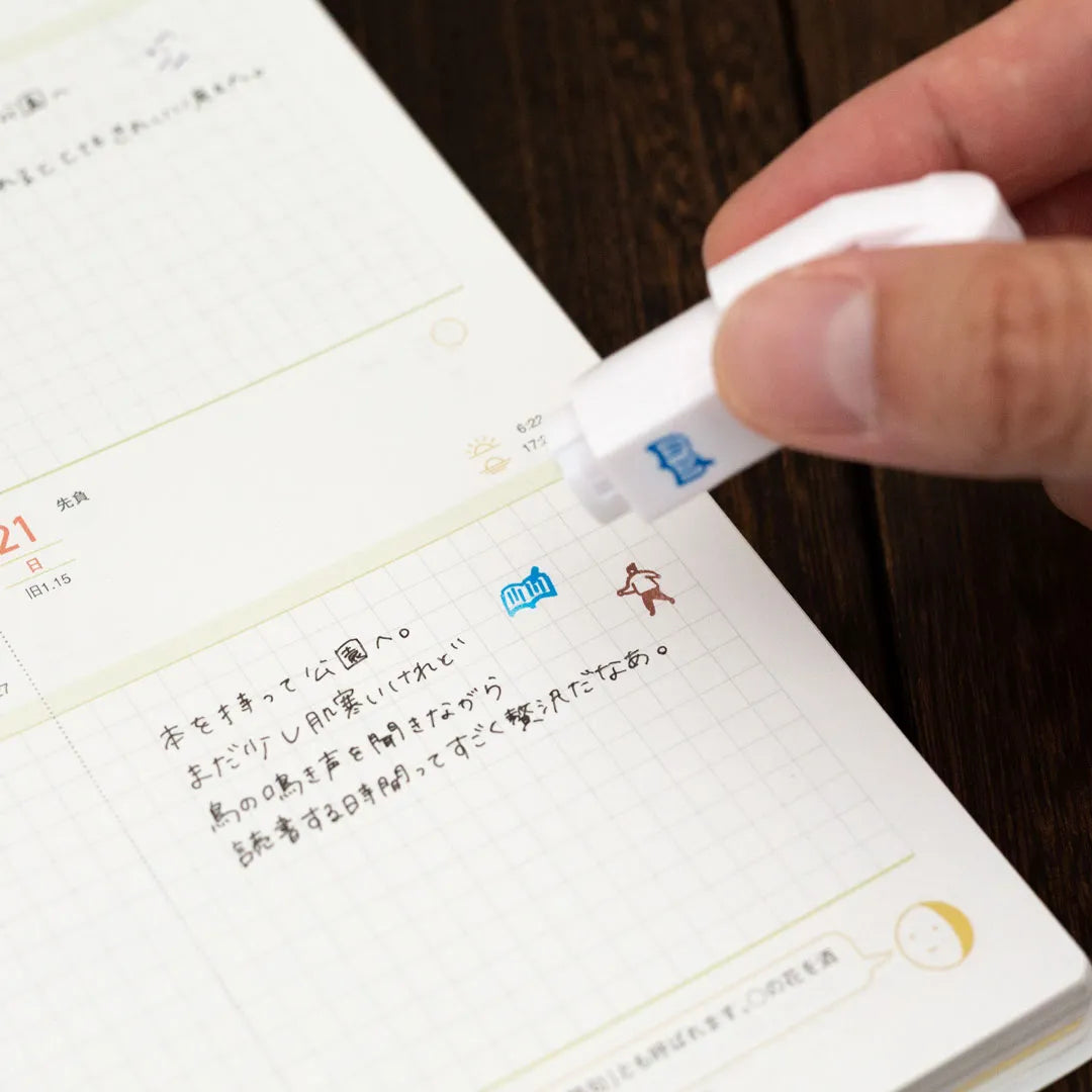Hand pressing a Totonofu stamp onto a planner page