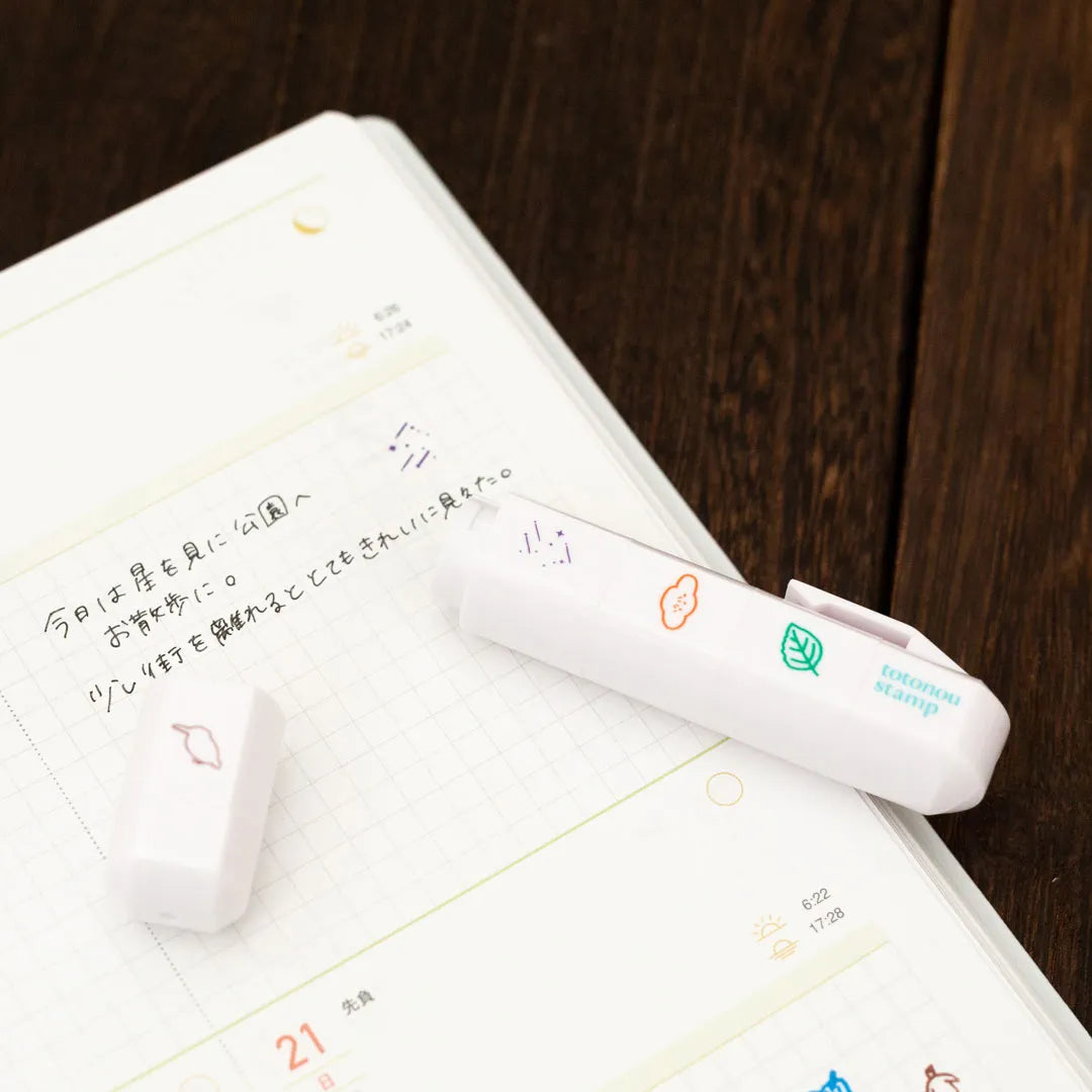 One Totonofu stamp twisted off its stick beside a planner