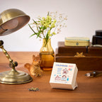 eric Colour Daily Calendar 2027 on a wooden desk beside a lamp and flowers