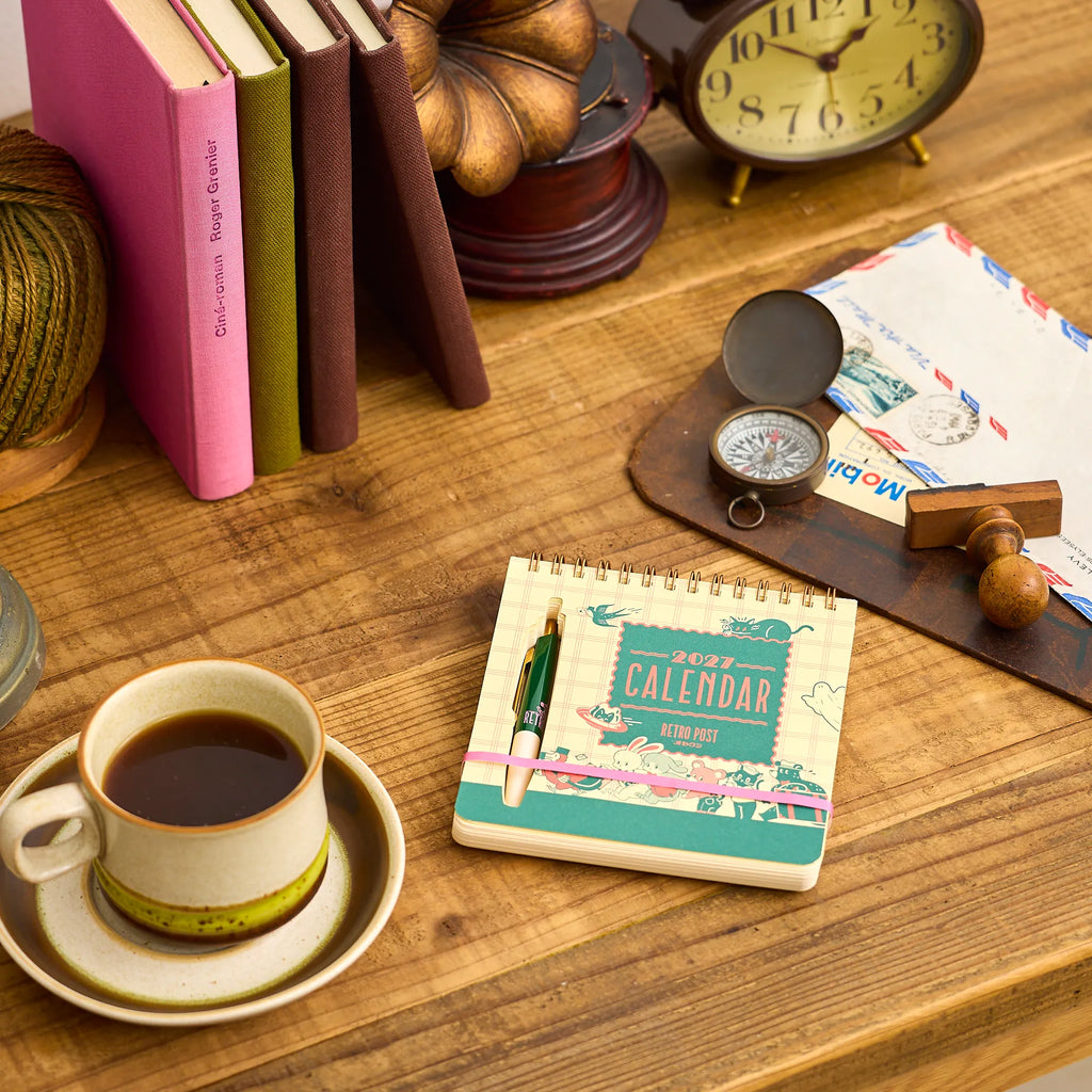 ob1toy Weekly Calendar 2027 on a wooden desk beside a cup of coffee