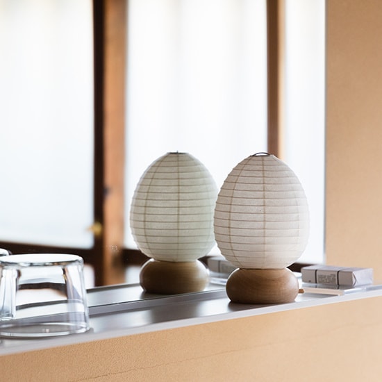 Two unlit Shiraki egg paper lanterns with wooden bases displayed side by side