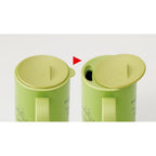 Diagram showing how to slide open the lid on a light green My Neighbor Totoro insulated mug