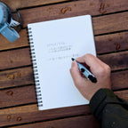 Light blue Tombow AirPress pen writing on wet paper in spiral notebook