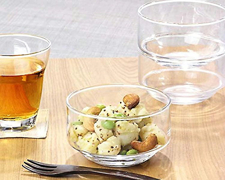 Open glass storage bowl with potato salad on wooden table