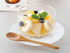Close up of clear glass canister holding fresh fruit salad and mint leaves