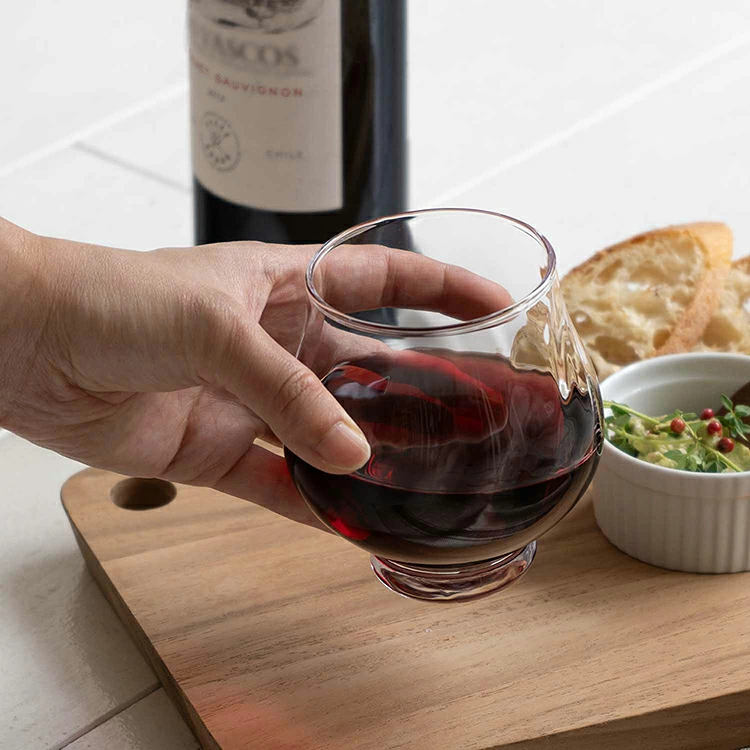 Hand holding Toyo Sasaki stemless wine glass with red wine over food