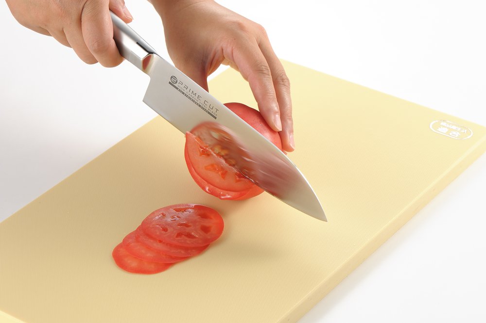 Slicing red tomato on Yoshikawa beige elastomer chopping board