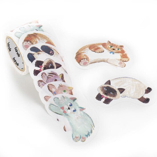 Unspooled roll of die-cut cat stickers showing orange tabby and Siamese designs