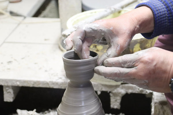 Hands throwing a cup on a potter's wheel