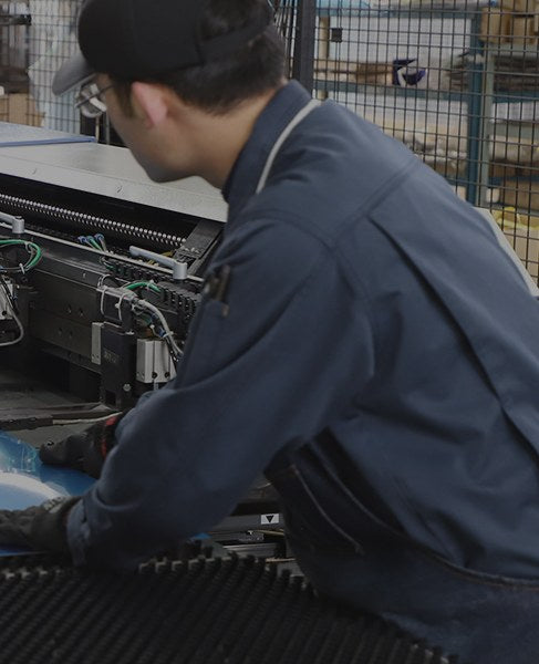 A worker loading a stainless steel sheet onto a press