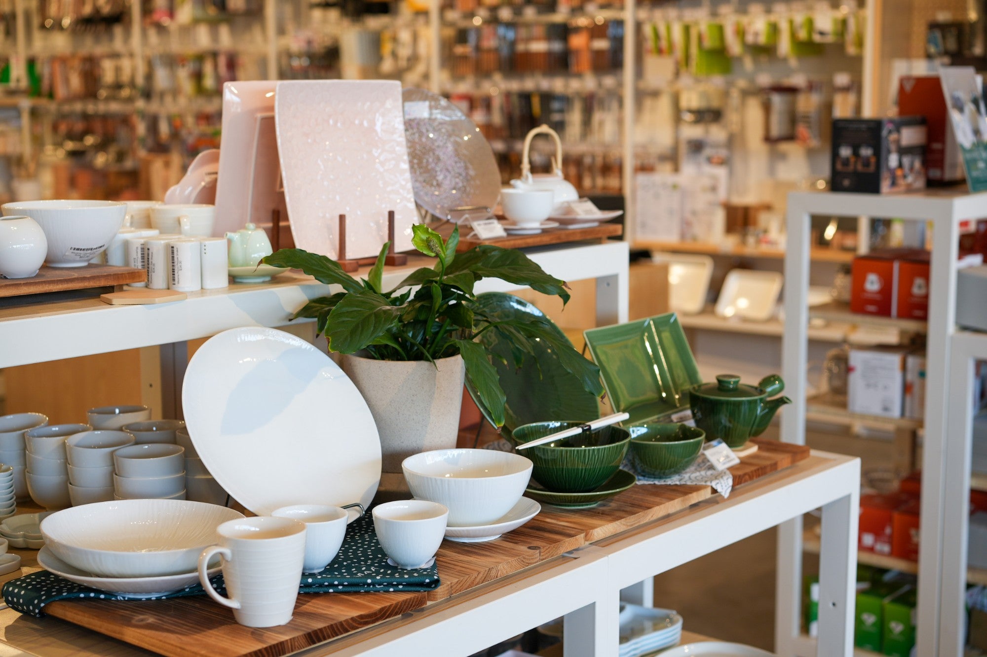 Japanese tableware display in the Minimaru store: plates, bowls, mugs and teapots on timber tables