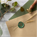 Green floral wax seal on brown envelope with eucalyptus