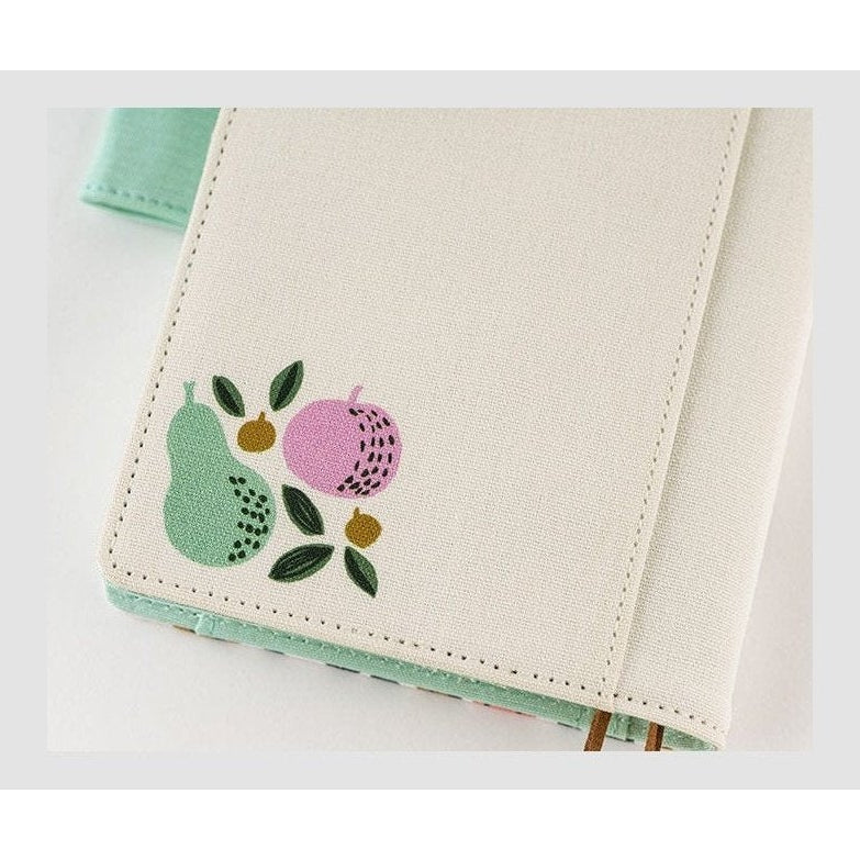 Close-up of Hobonichi Techo A6 planner corner detail showing stitched canvas edge and botanical fruit motif