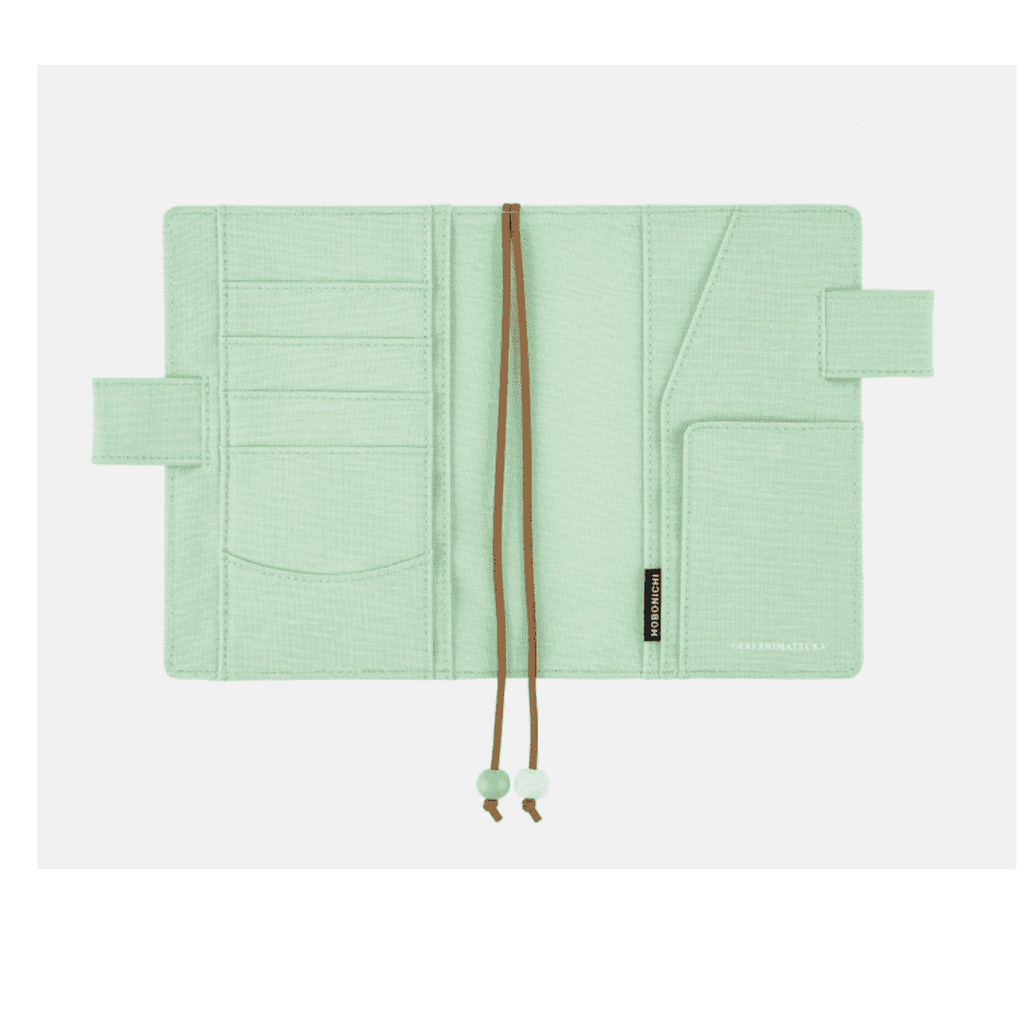 Interior view of Hobonichi Techo A6 planner cover showing mint green woven fabric pockets and HOBONICHI tag
