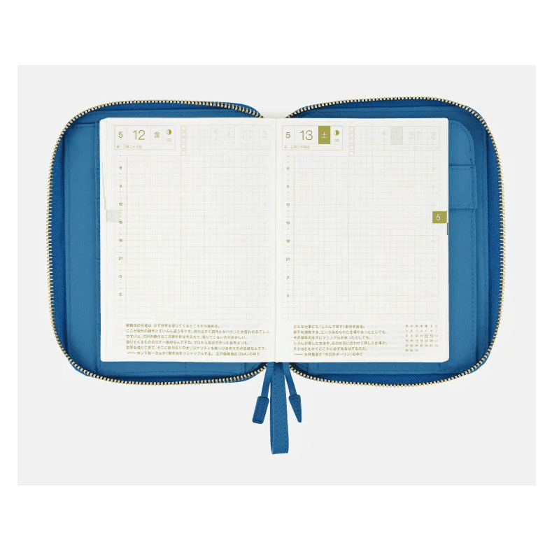 Open blue zippered Hobonichi planner displaying Friday and Saturday grid layouts with green tab