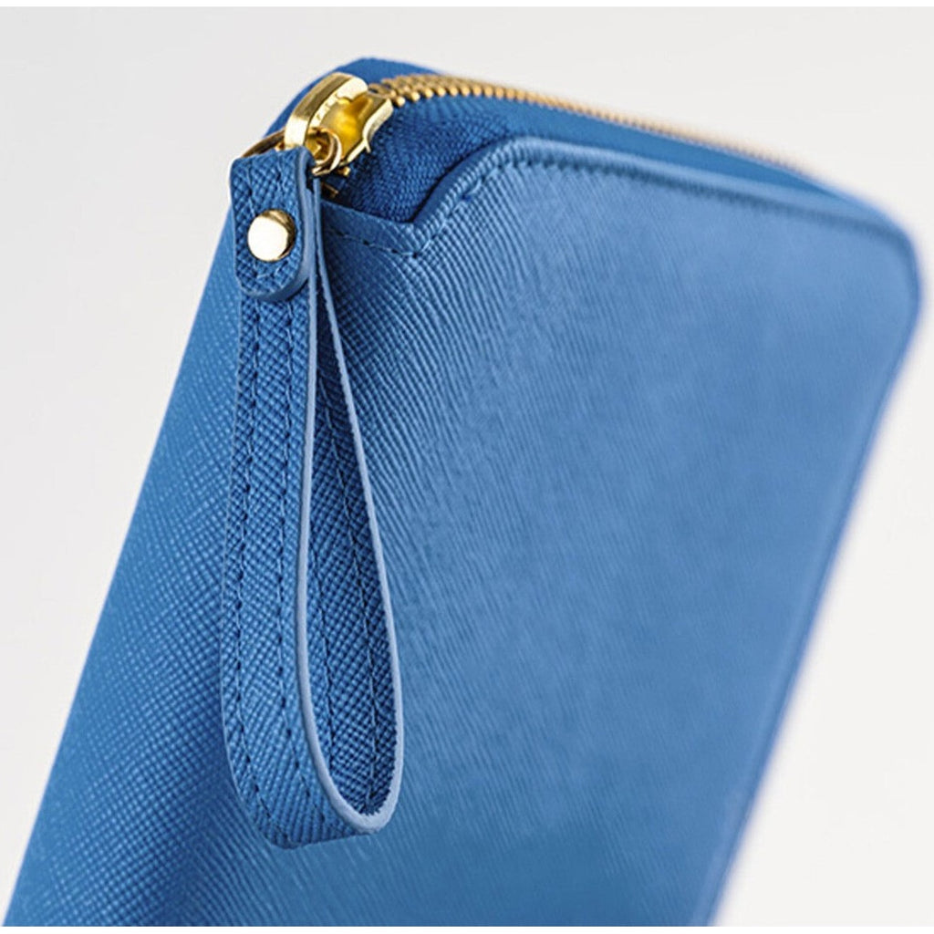 Close-up of blue Hobonichi cover corner showing gold zipper pull and stitched wrist strap