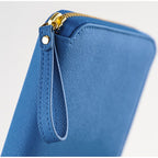 Close-up of blue Hobonichi cover corner showing gold zipper pull and stitched wrist strap