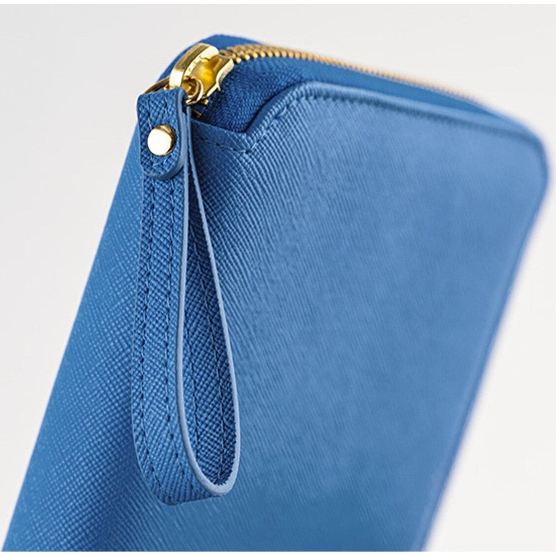 Close-up of blue Hobonichi cover corner showing gold zipper pull and stitched wrist strap