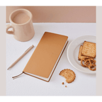 Diagonal tan Hobonichi Techo 2023 planner with beige pen and snack props