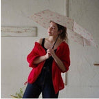 Woman holding open beige floral mini umbrella for sun protection