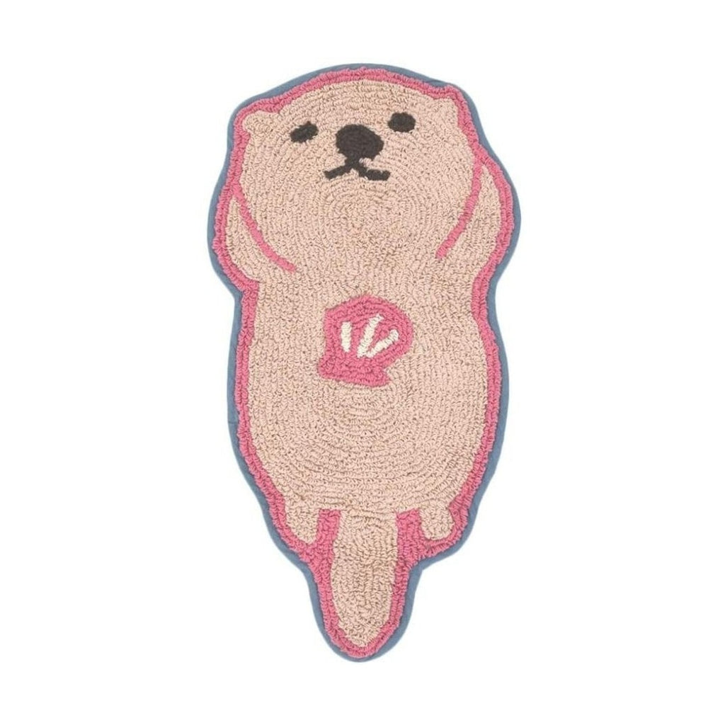 Beige sea otter shaped mat with pink shell design and blue border looped pile texture